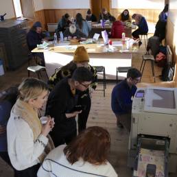 Artists in a printing workshop, people drawing and standing by the Risograph printer