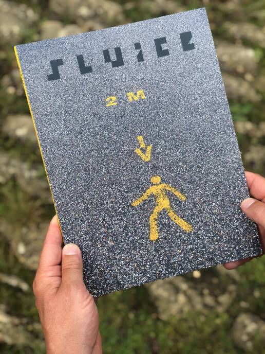 Front cover of SLUICE magazine, image on covertarmac with yellow 2m distance sign