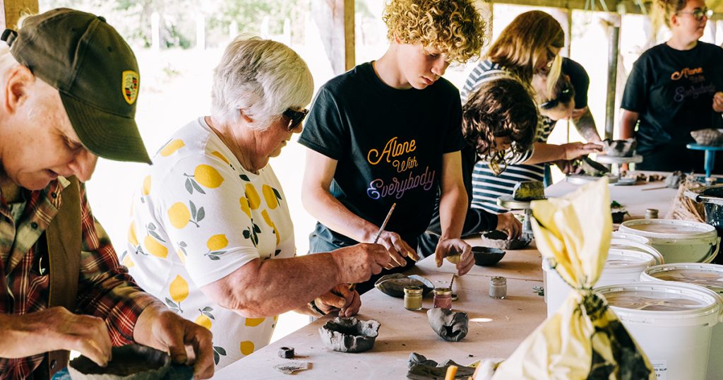 Young person working with two older people making clay pinch pots at dawes twineworks