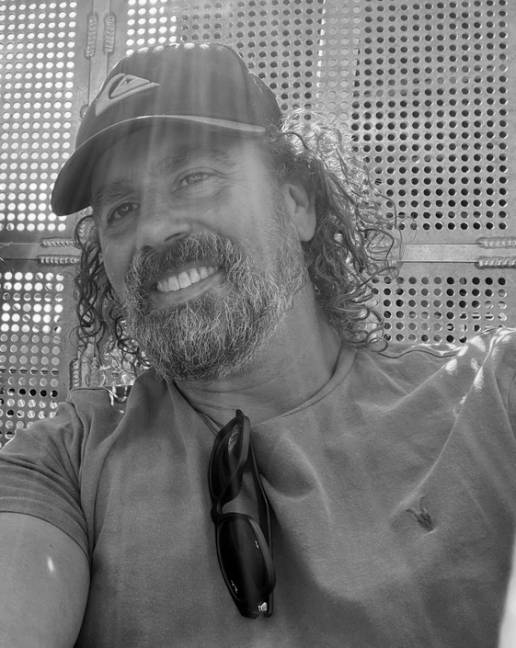 b/w photo of simon smiling wearing a baseball cap