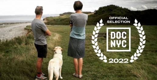 angela and dave and guide dog flynn standing with their back to us looking out to sea