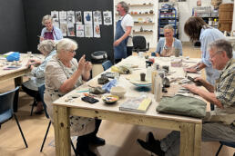 group of Thursday night potters in the studio, making 'clay things' around the large tables