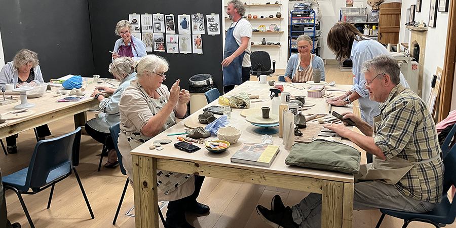 group of Thursday night potters in the studio, making 'clay things' around the large tables