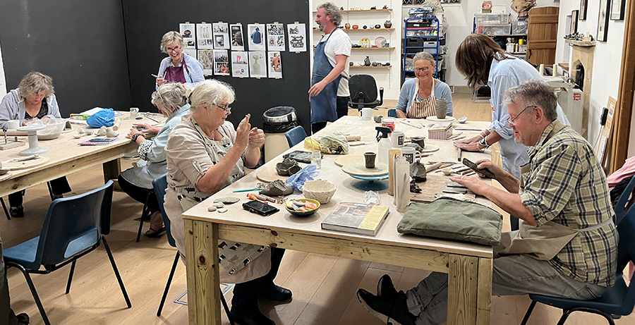 group of Thursday night potters in the studio, making 'clay things' around the large tables