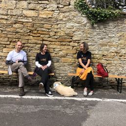 three Od Arts festival stewards sitting on a bench laughing.