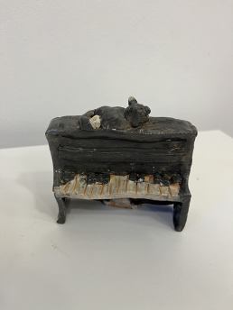 handbuilt tiny up right piano with a cat on top