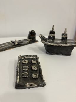 close up of handbuilt mobile phone and black and handbuilt white battle ships in the backgound