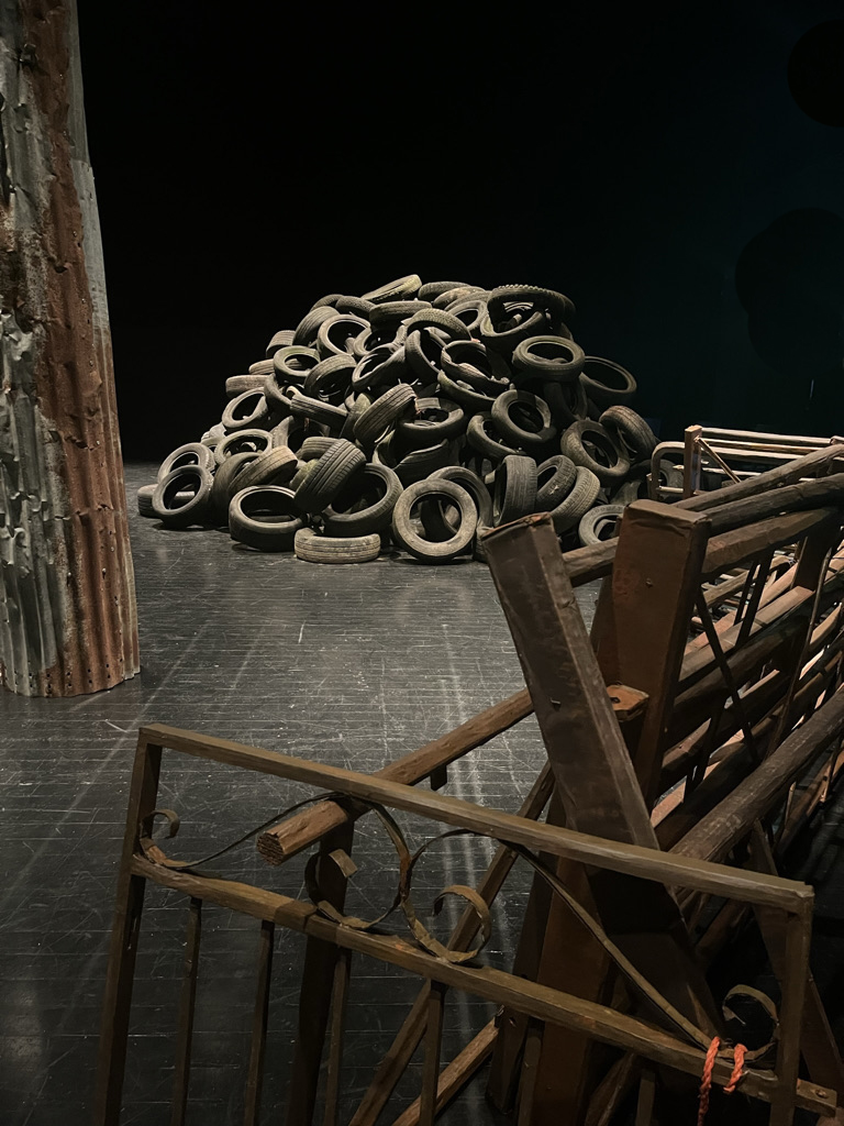 cropped image of gates pile of tyres in th background and on the ledt a corrigated column in a dark space