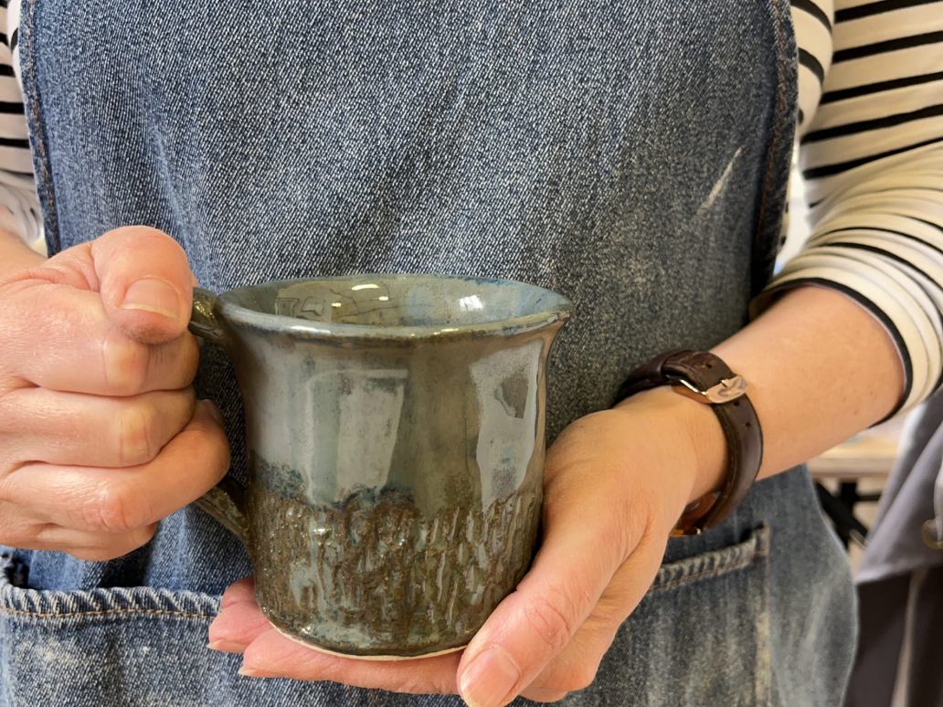 close up of hand holding a blue green mug