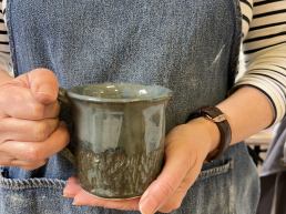 close up of hand holding a blue green mug