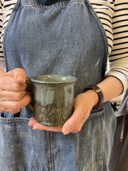 close up of hand holding a blue green mug