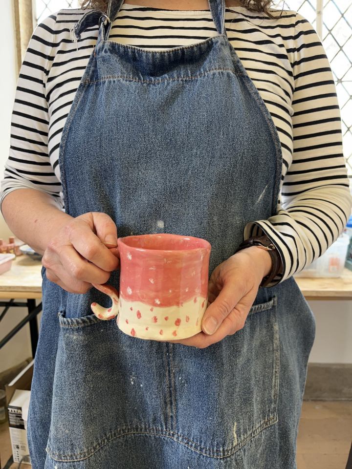 close up of hand holding a pink and white decorated mug