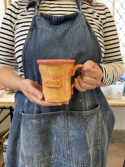 close up of hand holding an orange mug