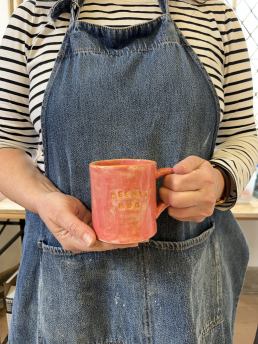 close up of hand holding a pink and orange mug